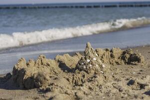 Waves and sand castle on the Baltic Sea beach photo