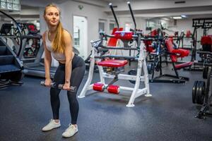 Young woman holds dumbbells in her hands and works out in the gym performing an exercise photo