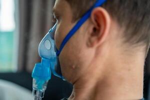 Unhealthy man wearing nebulizer mask in home. Health, medical equipment and people concept. High quality photo