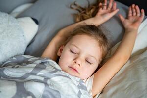 linda pequeño niña dormido con un juguete en su cama, siesta concepto foto