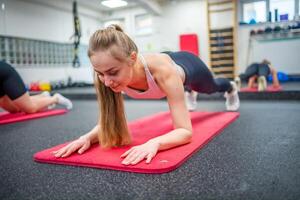 Young sport woman doing exercise in a plank position for the abs at gym, she exercise for strong and good healthy photo