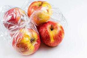 sano manzanas envuelto en transparente el plastico aislado en blanco antecedentes foto
