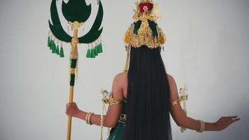 traseiro Visão do uma pessoa dentro tradicional balinesa traje segurando uma decorativo lança, contra uma branco fundo. video