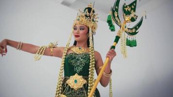 Woman in traditional Balinese dancer costume with ornate headdress and golden accessories, posing gracefully. video