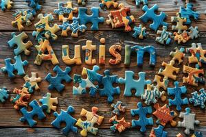 Colorful puzzle pieces frame and word Autism on wooden background. World autism awareness day concept. photo