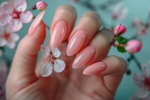 A delicate hand showcasing a manicure with pink gel polish complemented by a cherry blossom in the background photo