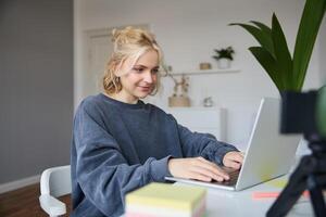 Portrait of young woman, student studying at home on remote education, working on laptop, typing on keyboard photo