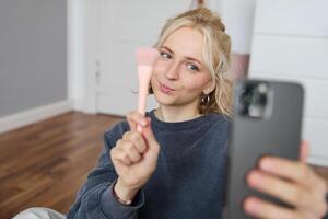 retrato de joven mujer, niña belleza bloguero, grabación vlog en su dormitorio, haciendo maquillaje tutorial para social medios de comunicación seguidores, tomando autofotos, En Vivo transmisión en móvil teléfono aplicación foto