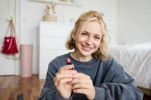 Portrait of young beautiful woman, content maker creating a new vlog, beauty , showing lipstick, recommending makeup, records a tutorial photo