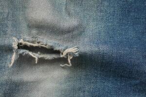 blue jean texture with a hole and ripped threads showing photo