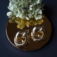 Golden earrings on a black background with decor photo