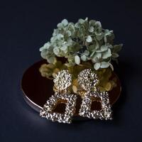 Golden earrings on a black background with decor photo