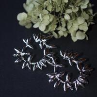 Silver earrings on a black background with flower photo