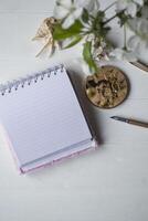 Opened notebook and spring flowers on a white wooden desk. photo