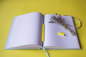 Opened planner with decor on a yellow background. Modern workplace. photo