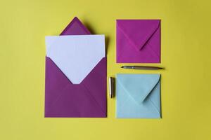 The colorful envelopes with note blank on the yellow background. Background with copy space. photo