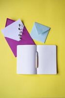 Opened notebook and colorful envelopes with note blank on the yellow background. Background with copy space. photo