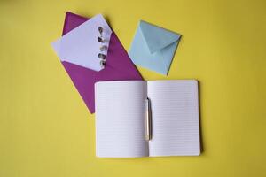 Opened notebook and colorful envelopes with note blank on the yellow background. Background with copy space. photo