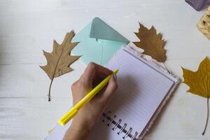 mujer escritura en el cuaderno. otoño hojas en el escritorio. foto