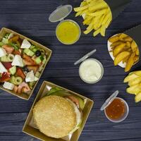 hamburguesa ensalada y francés papas fritas con salsas en el mesa. foto