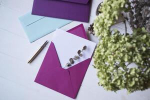 The pink envelope with note blank on the white wooden table. Beautiful desktop. Background with place for text. photo