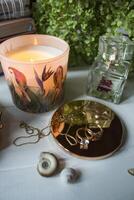 Candle, perfume bottle and jewels on a white table. photo