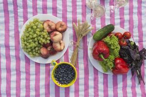 hermosa picnic con frutas, vegetales y lentes de vino cerca lago. foto