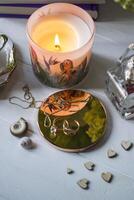 Candle, perfume bottle and jewels on a white table. photo