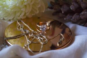 The golden chain and ring with diamond near flower, close up. photo