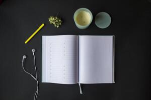 Opened planner with pen and head phones on the black table. Modern workplace. Background with copy space. photo