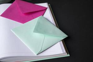 The turquoise and pink colors envelopes on the opened notepad, close up. photo