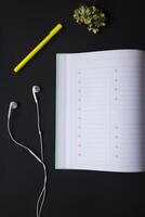 Opened planner with pen and head phones on the black table. Modern workplace. Background with copy space. photo