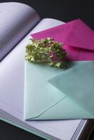 The turquoise and pink colors envelopes on the opened notepad, close up. photo