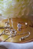 The golden chain and ring with diamond near flower, close up. photo