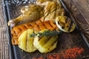 Grilled chicken and vegetables on a wooden table. photo