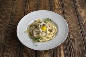 Pasta with parmesan, basil, and becon on a wooden table. Pasta carbonara. photo