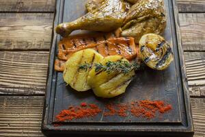 Grilled chicken and vegetables on a wooden table. photo