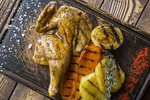 Grilled chicken and vegetables on a wooden table. photo