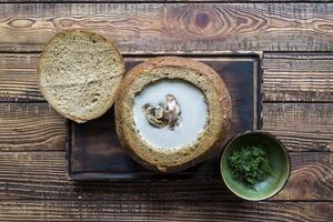 Cream soup in a bread, on a wooden table. photo