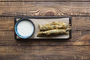 Fried capelin with sause on a wooden table. photo