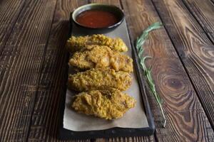 Fried chicken with sauce on a wooden table. photo