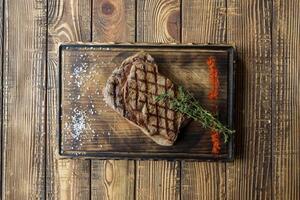 Grilled meat with sauce and rosemary on a wooden table. photo