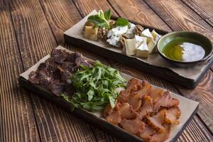 Cheese and meat plate on a wooden background. photo