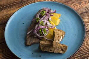 Fried potatoes and herring fish with onion on a wooden table. photo