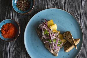 Fried potatoes and herring fish with onion on a wooden table. photo