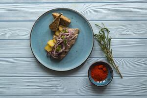 Fried potatoes and herring fish with onion on a wooden table. photo