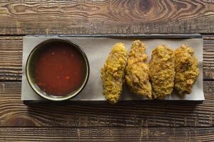 Fried chicken with sauce on a wooden table. photo