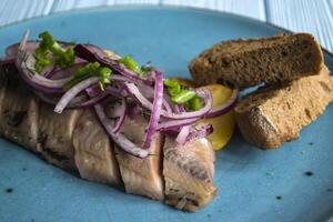 Fried potatoes and herring fish with onion on a wooden table. photo