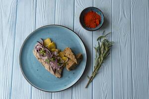 Fried potatoes and herring fish with onion on a wooden table. photo