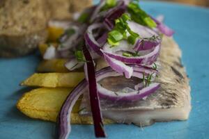 Fried potatoes and herring fish with onion on a wooden table. photo